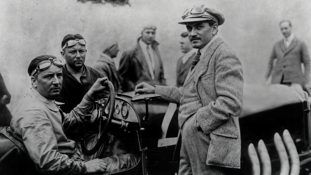 Ο Ferdinand Porsche (όρθιος, με το καπέλο) δίπλα σε αγωνιστικό αυτοκίνητο της Mercedes, στα χρόνια που δούλευε στη Daimler.