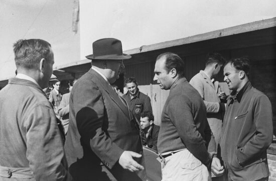 Ο Fangio (στη μέση, με το πουλόβερ) με τον θρυλικό διευθυντή της Mercedes, Alfred Neubauer (με το καπέλο), στο Grand Prix της Ολλανδίας το 1955.